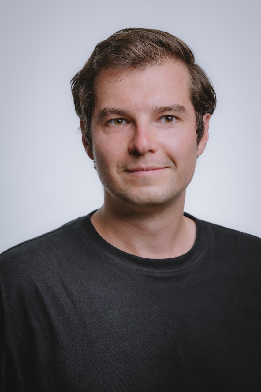 Portrait von Michael Prader im schwarzen T-Shirt vor hellem Hintergrund