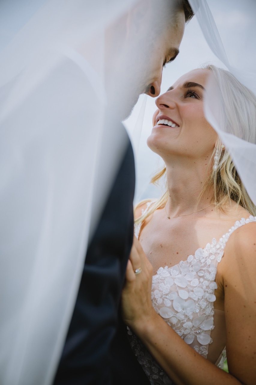 Brautpaar blickt sich unter dem Schleier lachend an — Nahaufnahme