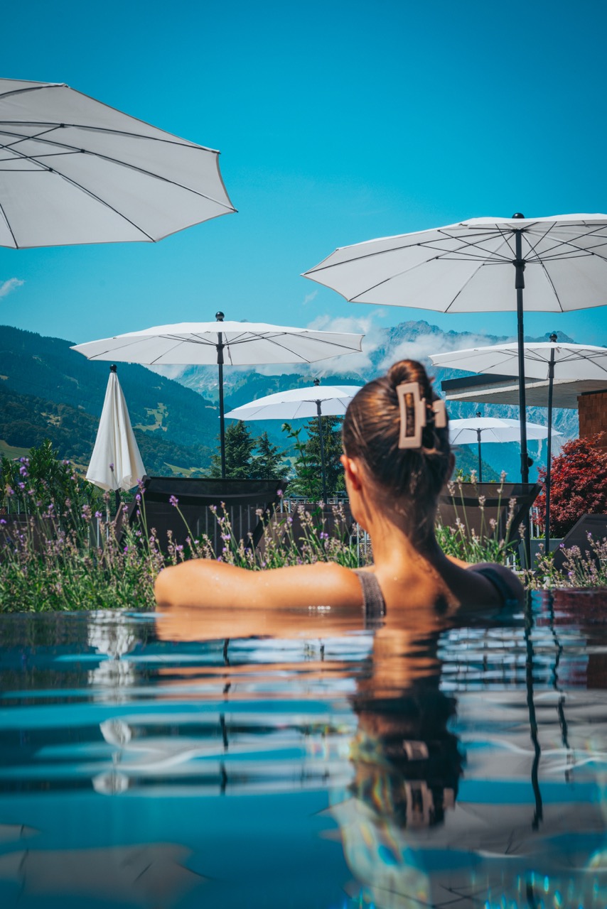Frau entspannt im Infinity-Pool mit Blick auf die Berge
