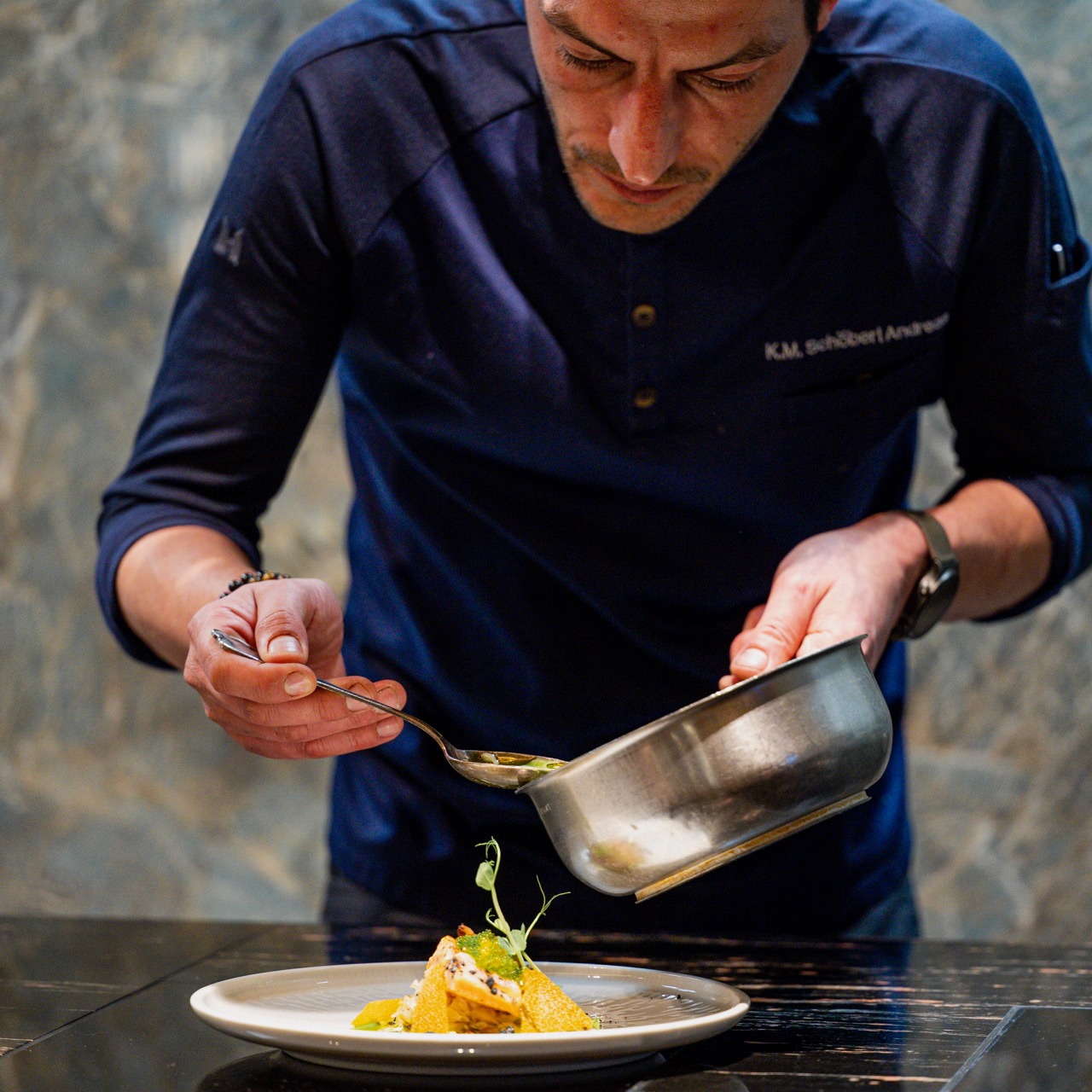 Koch richtet ein Gericht an — Nahaufnahme beim Anrichten in der Küche