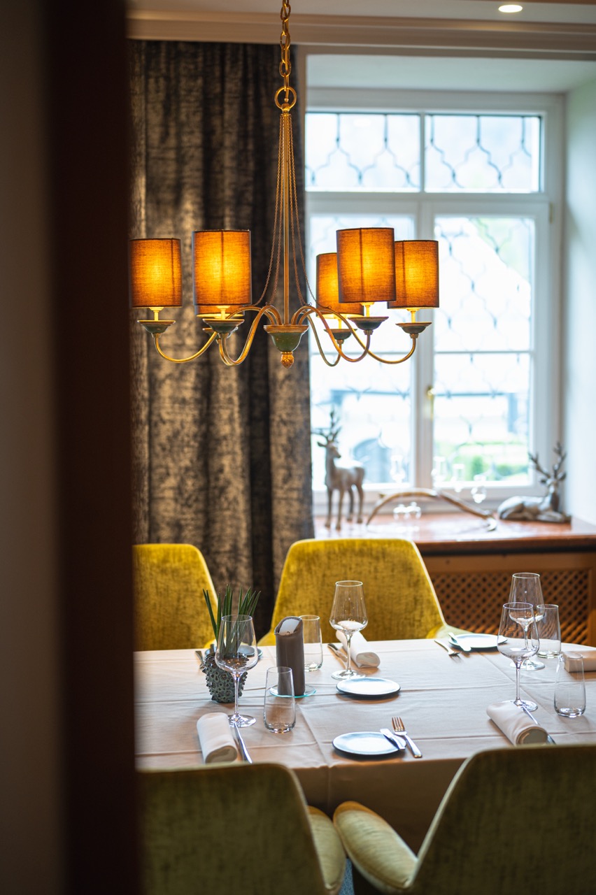 Elegant gedeckter Restauranttisch mit Kronleuchter und Samtsesseln