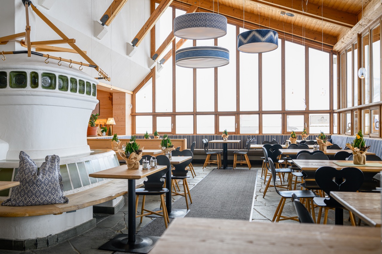 Lichtdurchfluteter Hotelrestaurant-Saal mit Kachelofen und Panoramafenstern