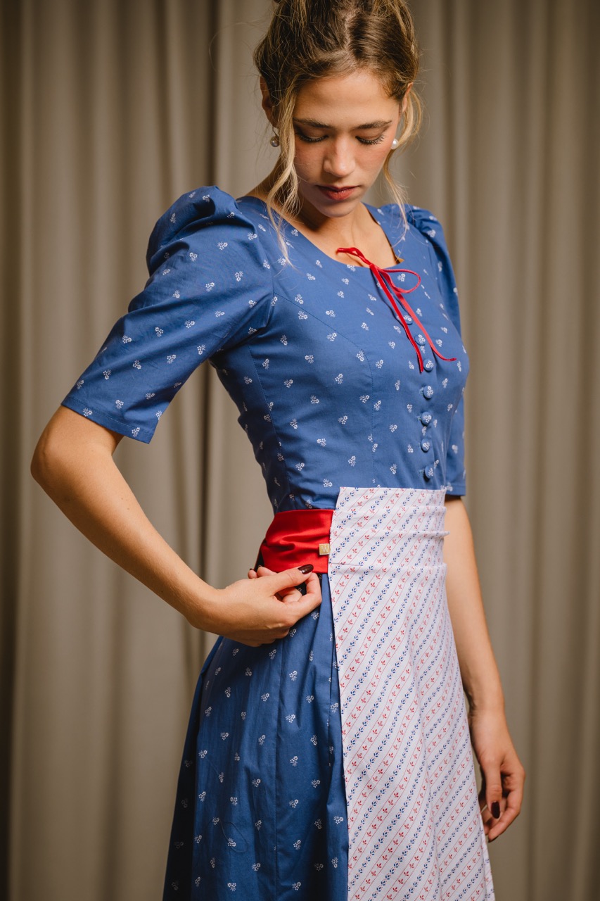 Junge Frau in blauem Dirndl mit roter Schleife — Modefotografie