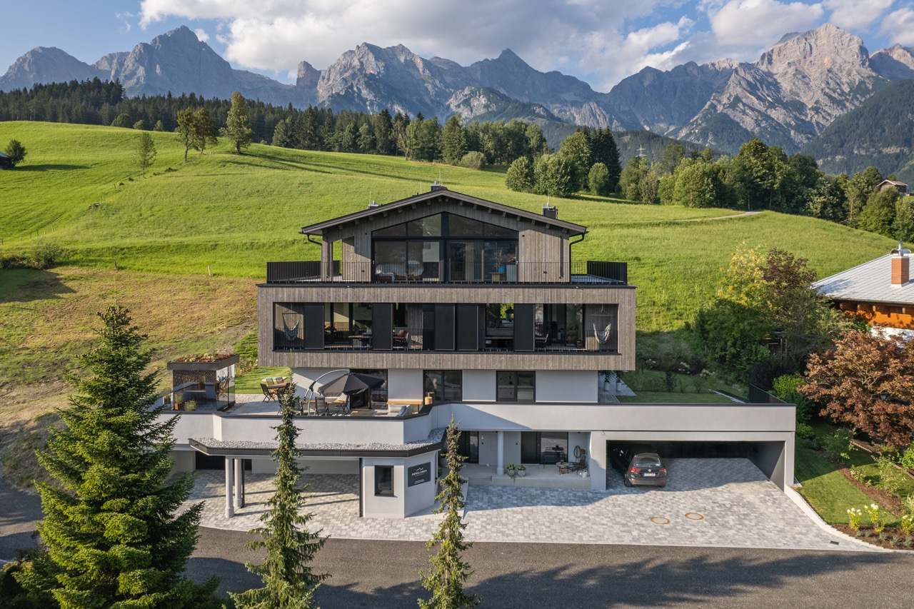 Modernes Architekturhaus mit Glasfassade vor Bergkulisse — Drohnenaufnahme