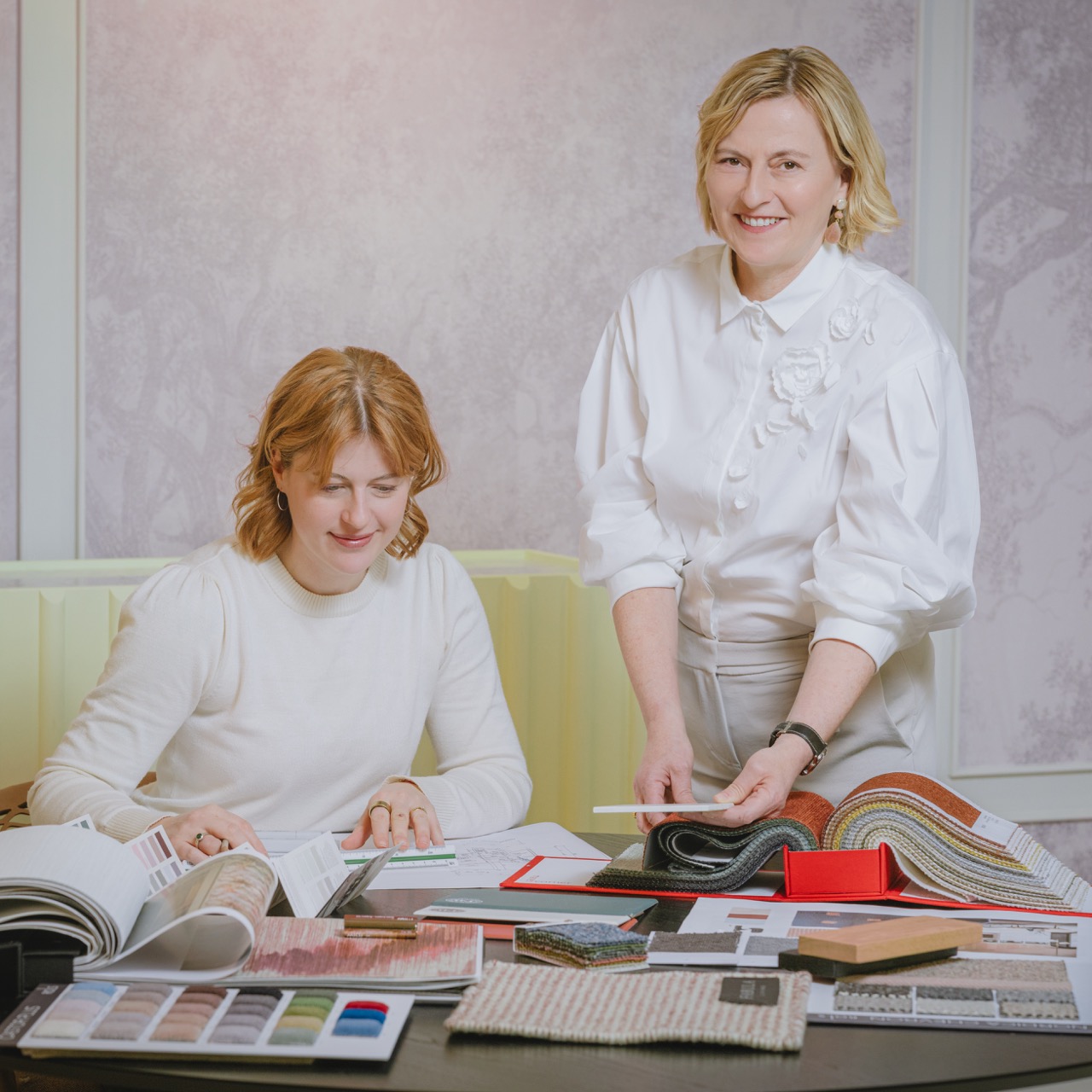Zwei Innenarchitektinnen mit Stoffmustern und Materialbüchern am Arbeitstisch