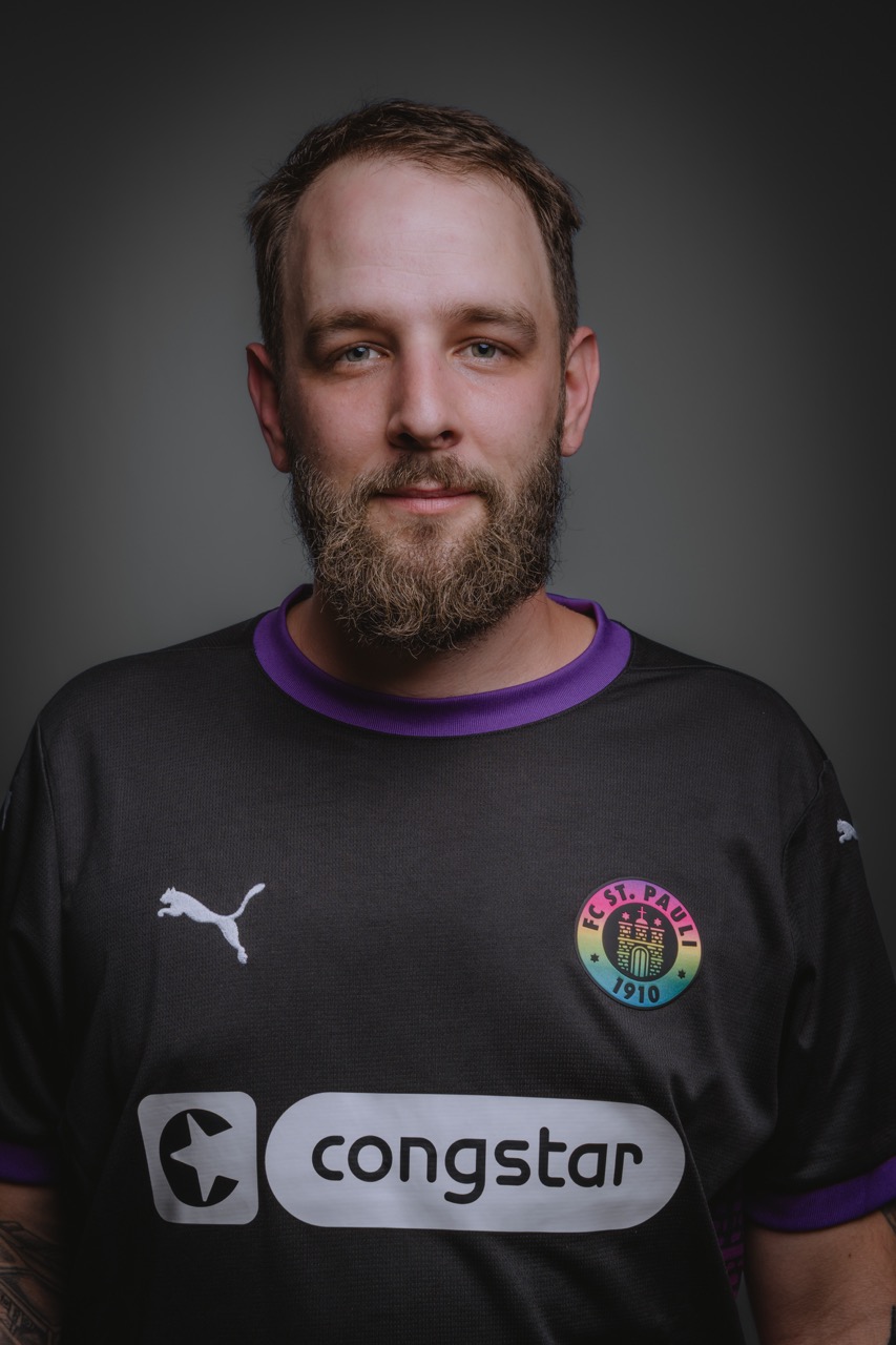 Charakterportrait eines jungen Mannes im dunklen Shirt vor grauem Hintergrund