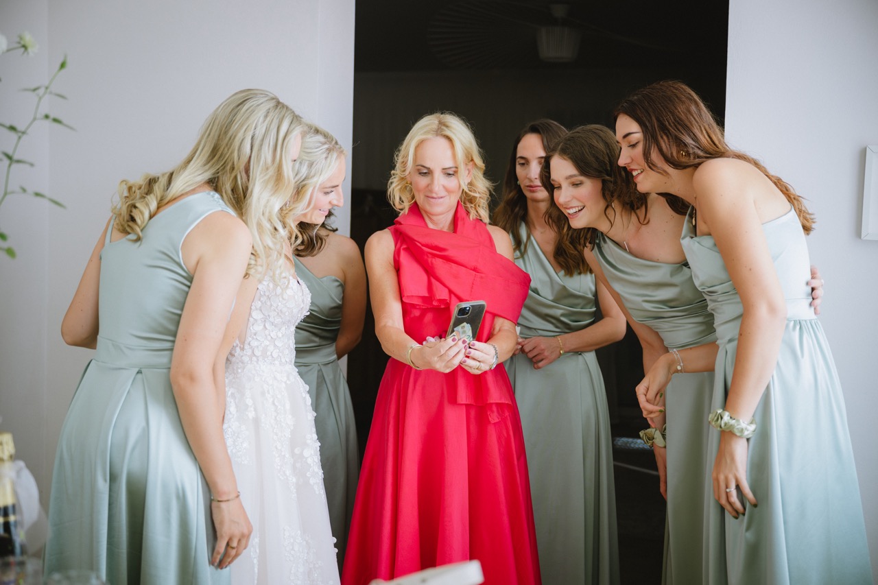 Getting Ready — Braut und Brautjungfern schauen lachend aufs Handy